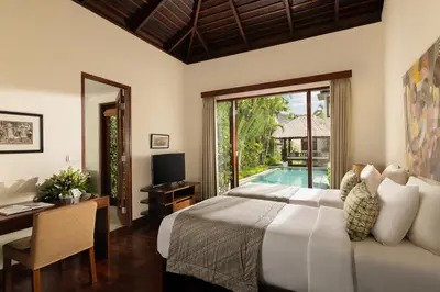 a bedroom with a bed and a desk and a pool at The Suar Seminyak by Nakula in Seminyak