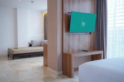 a hotel room with a bed and a flat screen tv at Cross Vibe Paasha Atelier Bali Kuta in Kuta