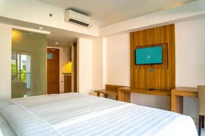 a bedroom with a bed and a flat screen tv at Cross Vibe Paasha Atelier Bali Kuta in Kuta