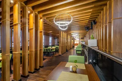 a hallway with wooden columns in a restaurant with tables and chairs at Cross Vibe Paasha Atelier Bali Kuta in Kuta