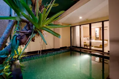 a swimming pool in a hotel room with a plant at Cross Vibe Paasha Atelier Bali Kuta in Kuta