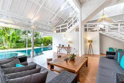 an open living room with a table and a pool at La Villa Oberoi (6 BR) in Seminyak