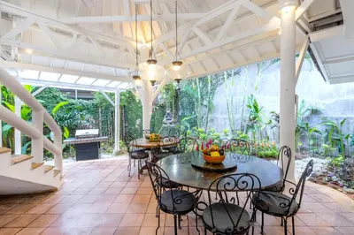 a patio with tables and chairs and trees at La Villa Oberoi (6 BR) in Seminyak