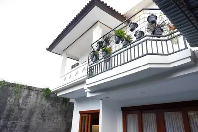 a white house with a balcony with potted plants at Villa Bale Damai Denpasar in Seminyak