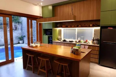 a kitchen with a large wooden island with bar stools at Villa Bale Damai Denpasar in Seminyak