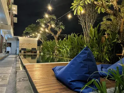 a pool in a house with a blue pillow on a wooden deck at Legian Bisma Suite in Seminyak