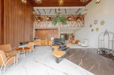 a lobby with tables and chairs and a staircase at Horison Le Aman Bali in Jimbaran