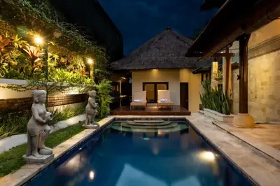 a swimming pool in front of a villa at night at Villa Tunjung Batubelig Canggu in Canggu