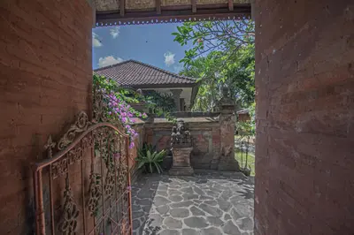 an entrance to a house with a fence and flowers at Panorama Cottages I in Legian