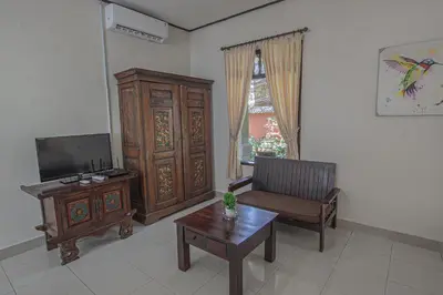 a living room with a tv and a chair and a table at Panorama Cottages I in Legian