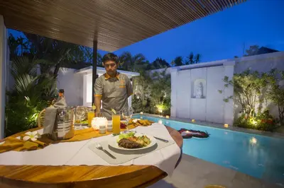 a man standing in front of a table with a plate of food at The Kon's Villa Bali Seminyak in Seminyak