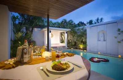 a table with a plate of food next to a pool at The Kon's Villa Bali Seminyak in Seminyak