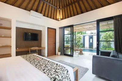 a bedroom with a bed and a tv andwindows at The Kon's Villa Bali Seminyak in Seminyak