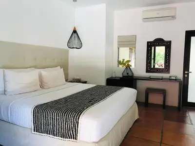 a bedroom with a large white bed and a desk at Villa Elleo in Seminyak