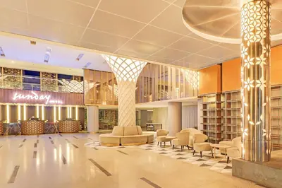 a lobby with a library with chairs and tables at Sunday Hotel Arshika Sunset Road in Kuta