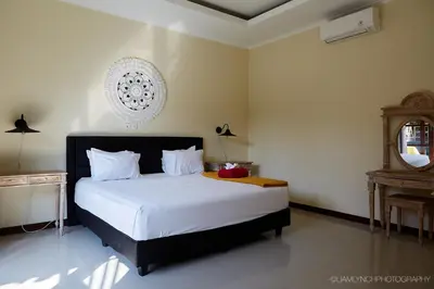 a bedroom with a large white bed with a mirror at Villa Nicola in Seminyak