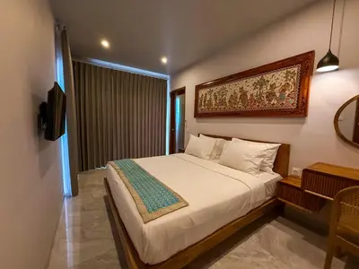 a bedroom with a bed with a painting on the wall at Rahayu Guest House Seminyak in Seminyak