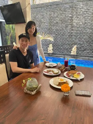 a man and a woman sitting at a table with food at Rahayu Guest House Seminyak in Seminyak