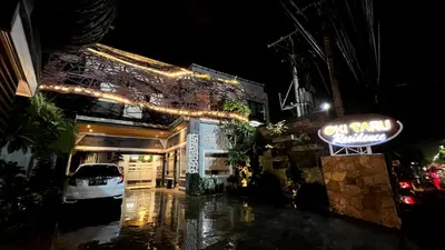 a lit up sign in front of a building at night at Oki Taru Residence in Kuta