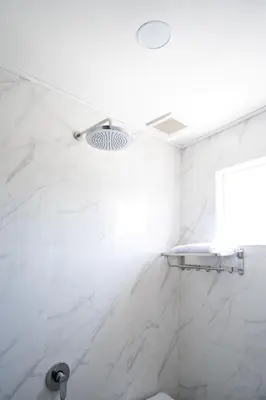 a bathroom with white marble walls and a shower at Oki Taru Residence in Kuta
