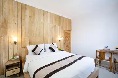 a bedroom with a large bed and a wooden wall at Oki Taru Residence in Kuta
