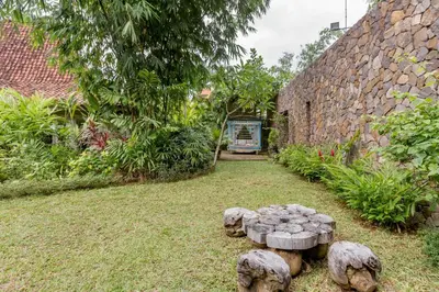 a garden with stone walls and trees and stone benches at Wahyu wonderful 4Bd villa with huge garden and 2 pools in Seminyak