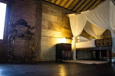 a bedroom with a canopy bed and a brick wall at Wahyu lux honeymoon joglo 2 in Seminyak