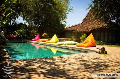 a swimming pool with colorful pillows next to a house at Wahyu lux honeymoon joglo 2 in Seminyak