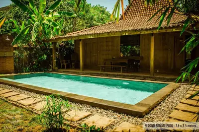 a swimming pool in front of a house at Wahyu lux honeymoon joglo 2 in Seminyak