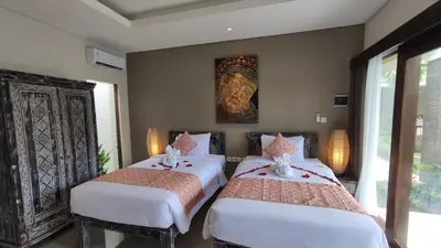 two beds in a room with a painting on the wall at Kubu Garden Suites & Villas Nusa Dua in Nusa Dua