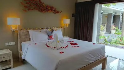 a bedroom with a white bed with red flowers on it at Kubu Garden Suites & Villas Nusa Dua in Nusa Dua
