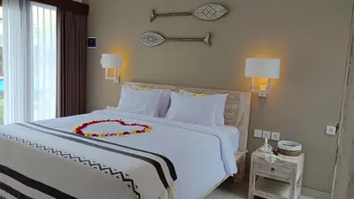 a bedroom with a large white bed with a red flower on it at Kubu Garden Suites & Villas Nusa Dua in Nusa Dua