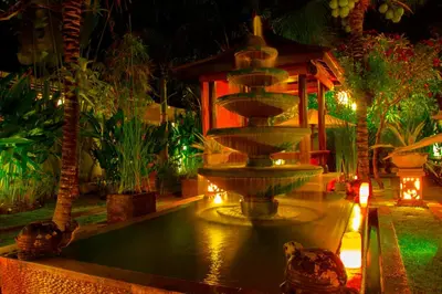 a fountain in the middle of a garden at night at Kubu Garden Suites & Villas Nusa Dua in Nusa Dua