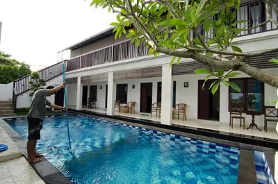 a man is standing next to a swimming pool at Sanur Guest House in Sanur