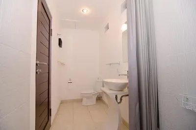 a white bathroom with a toilet and a sink at Sanur Guest House in Sanur