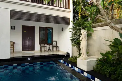 a villa with a swimming pool and a statue at Sanur Guest House in Sanur