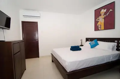 a bedroom with a bed and a flat screen tv at Sanur Guest House in Sanur
