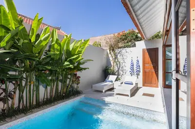 a swimming pool next to a house with plants at Villa Bella Seminyak in Seminyak