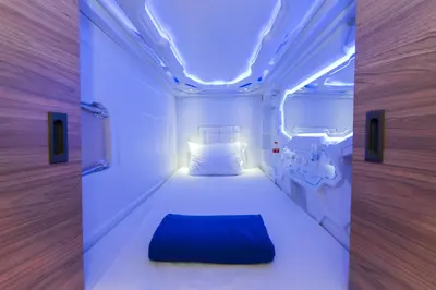 a bedroom with a white bed with a blue pillow at PassGo Digital Airport Hotel Bali in Kuta
