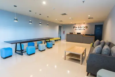 a lobby with a long table and blue chairs at PassGo Digital Airport Hotel Bali in Kuta