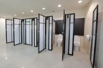 a row of stalls in a bathroom with toilets at PassGo Digital Airport Hotel Bali in Kuta