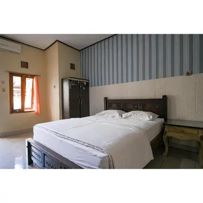 a bedroom with a large bed with white sheets at Pondok Syariah Denpasar Mitra RedDoorz in Kerobokan