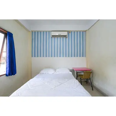 a small bedroom with a bed and a table at Pondok Syariah Denpasar Mitra RedDoorz in Kerobokan