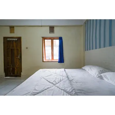 a large bed in a room with a window at Pondok Syariah Denpasar Mitra RedDoorz in Kerobokan