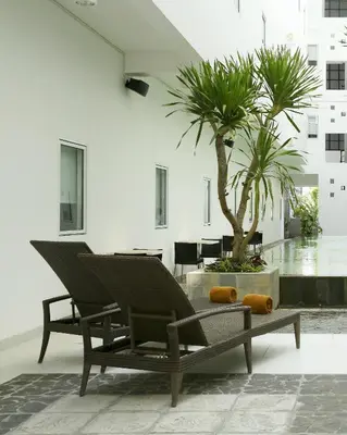 a patio with two chairs and a palm tree at Amaris Hotel Sunset Road - Bali in Kuta
