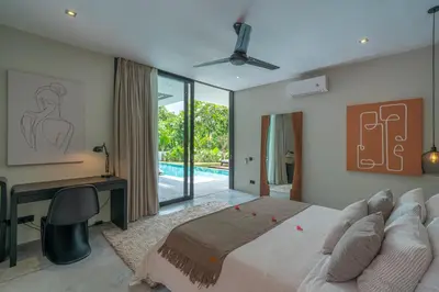 a bedroom with a bed and a desk and a pool at Villa Prana - High End Boutique Style Interior Design 5 BR Villa in Canggu