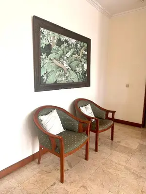 two chairs in a room with a painting on the wall at Turtledove Guesthouse in Kerobokan