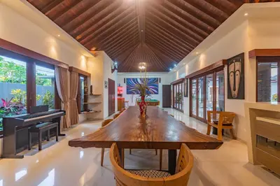 a dining room with a wooden table and a piano at 5 BR Villa Sultan Luxury Entertainment and Relaxation in Seminyak