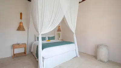 a bedroom with a white bed with a canopy at Villa Aloui by Villa Finder in Kerobokan