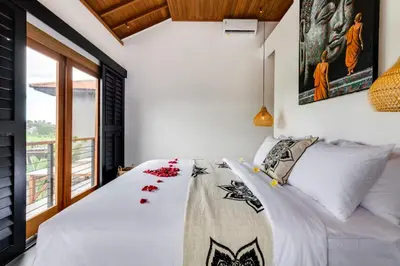 a bedroom with a bed with white sheets and a window at 2 Zen Bali Villa Canggu in Canggu